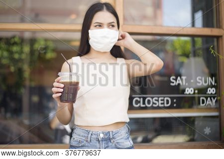 Beautiful Woman With Face Mask Is Holding Coffee In Front Of Coffee Shop