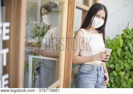 Beautiful Woman With Face Mask Is Holding Coffee In Front Of Coffee Shop