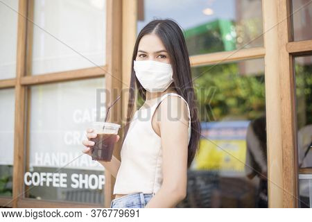 Beautiful Woman With Face Mask Is Holding Coffee In Front Of Coffee Shop