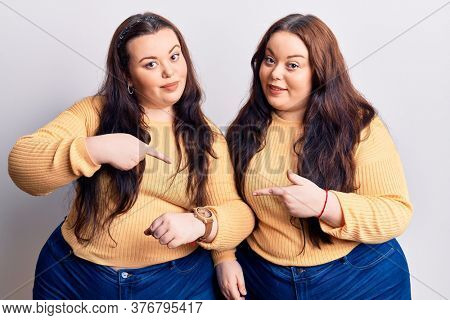 Young plus size twins wearing casual clothes in hurry pointing to watch time, impatience, upset and angry for deadline delay 