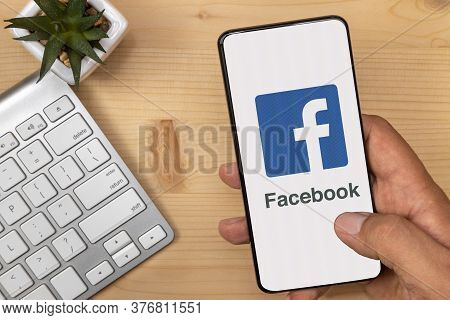 Lutsk, Ukraine - July 17, 2020: Hand Holding And Tapping Smartphone With Facebook Logo On It With Ac