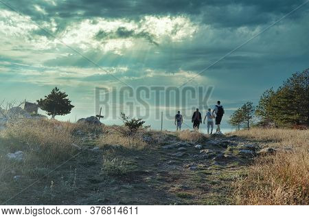Four Friends Hiking Together, Reach The Top Of A Small Hill, Stone Path Overgrown With Grass Leading
