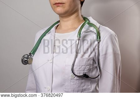 Green Stethoscope. A Doctor In A White Medical Uniform And Gloves Holds A Stethophonendoscope.