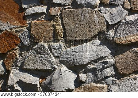 Wall Background Paved With Stones Of Different Irregular Shapes On Cement Mortar.