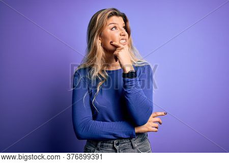 Young beautiful blonde woman wearing casual t-shirt over isolated purple background Thinking worried about a question, concerned and nervous with hand on chin