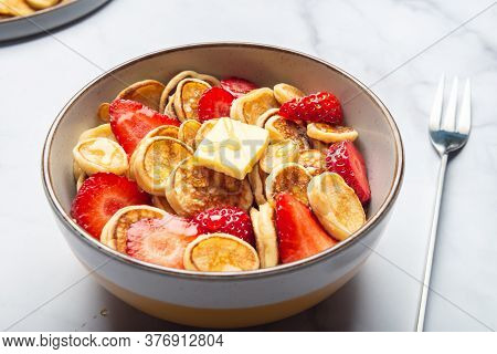 Trendy Home Breakfast With Tiny Cereal Pancakes With Piece Of Butter And Fresh Strawberries In The B