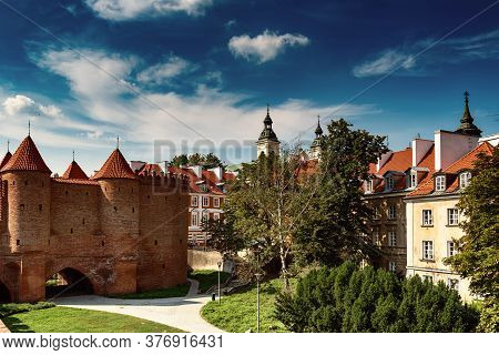 Warsaw, Poland Summer View Of Barbican Or Barbakan Wall And Old Town Houses With Green Trees And Blu