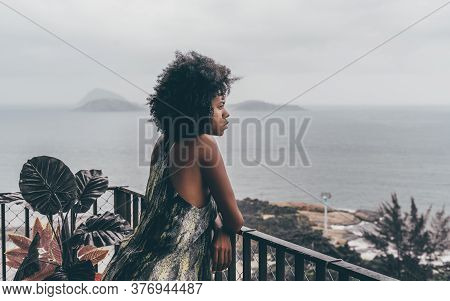 A Young Sleepy Brazilian Girl Is Leaning Against A Balcony Fence And Looking On A Morning Rainy Land