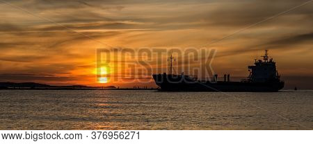 Sunset By The Sea - An Evening Landscape By The Sea Coast And A Ship Going To The Port