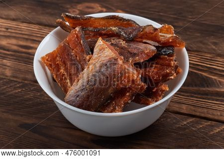 Pieces Of Cleaned Dried Fish Isolated On Wooden Background. Dry Peppered Pollack. Amber With Pepper.