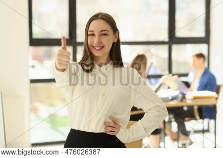 Portrait Of Smiling Woman Posing In Office And Showing Thumb Up Sign. Well Done, Good Job Concept