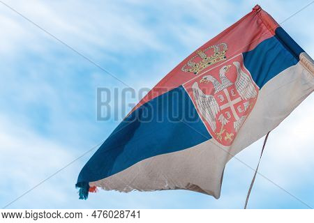 Torn And Weathered Flag Of Serbia On A Post Waving In Wind, Selective Focus