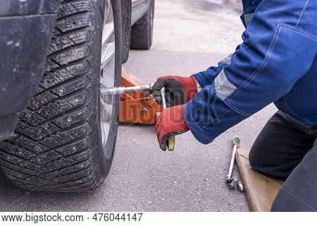 Mechanic Installs And Screws The Wheel On The Car With Ratchet Wrench