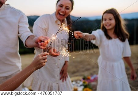 Happy Family With Children Having Picnic In Park, Clebrating With Sparklers.