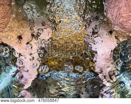 Young Man's Feet Immersed In A Water Tank Where Fish Called 