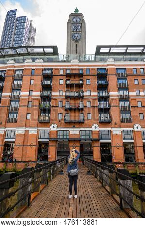 London - April 21, 2023: A Female Photographer Takes A Picture Of The Oxo Tower Wharf From A Wooden 