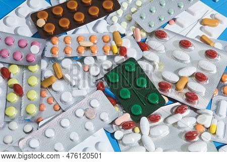 A Large Pile Of Pills In Bundles Scattered On The Table. A Mound Of Multi-colored Tablets And Bliste