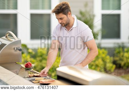 Man At A Barbecue Grill. Male Cook Preparing Barbecue Outdoors. Bbq Meat, Grill For Picnic. Roasted 
