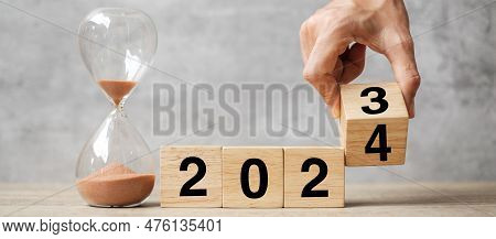 Hand Flipping Block 2023 To 2024 Text With Hourglass On Table. Resolution, Time, Plan, Goal, Motivat