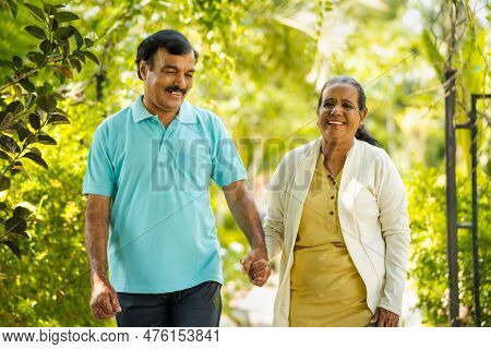 Indian Senior Couple Walking By Talking Each Other At Park - Concept Of Relationship, Relaxation And