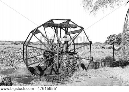 Keimoes, South Africa - Feb 25, 2023: An Irrigation Canal, Working Waterwheel Replica And Vineyard, 