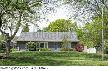 Tree Surrounded Gray House With Flowering Lilac Bush