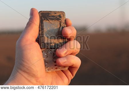 Damaged Phone Held In Hand - E-waste Disposal Challenge Concept.