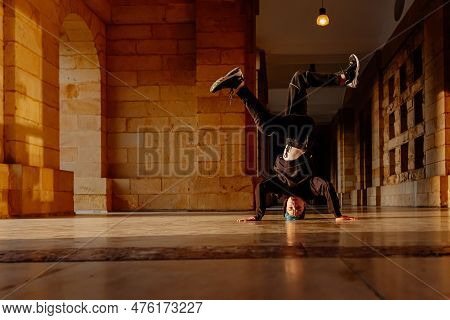 Boy In His Teens Break Dancing On A Tiled Floor In The Arcades Of A Historic Building. Street Dancer