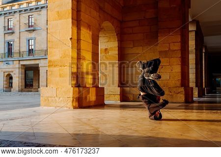 Boy In His Teens Break Dancing On A Tiled Floor In The Arcades Of A Historic Building. Street Dancer