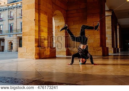 Boy In His Teens Break Dancing On A Tiled Floor In The Arcades Of A Historic Building. Street Dancer