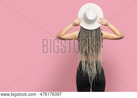 Woman With Long African Braids And Hat On Pink Background, Back View. Space For Text