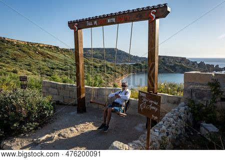 Ghajn Tuffieha, Malta - April 17, 2023: Man Relaxing On A Wooden Swing At Scenic Mediterranean Sea V