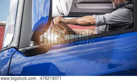 European Caucasian Semi Truck Driver In His 40s Behind The Wheel Side View. Euro Cargo Transportatio