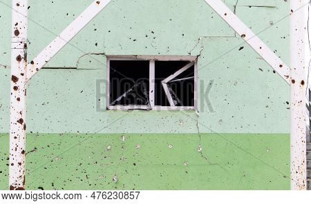 The Wall Of A Building Battered By Rocket Fragments In A War Zone. Shelled Wall. Facade Of A Bombed-