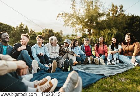 Happy Multi Generational People Having Fun Sitting On Grass In A Public Park - Diversity And Friends