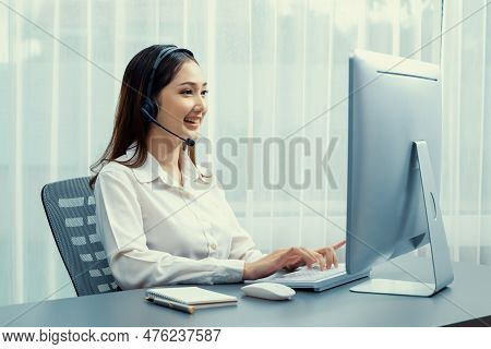 Asian Call Center With Headset And Microphone Working On Her Laptop. Female Operator Provide Excepti