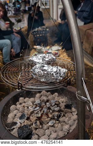 Potato In Alumnium Foil Baked On Charcoal Barbecue Grill Outdoor