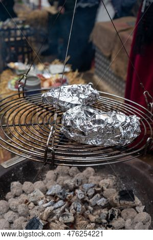 Potato In Alumnium Foil Baked On Charcoal Barbecue Grill Outdoor