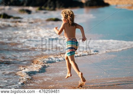 Child Running Through Water Close To Shore Along The Sea Beach. A Boy Runs Along The Sea Coast. Rest