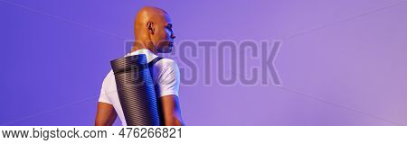 Back View Of Fitness Man Holding Rolled Up Exercise Mat On Studio Background With Color Filter