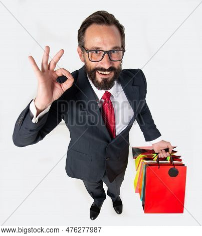 A Handsome Bearded Man With Shopping Bags In Hands And Ok Sigh Gesturing. Man In Suit Makes Exelent 