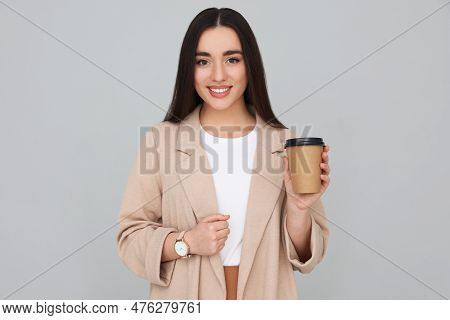 Young Female Intern With Cup Of Drink On Grey Background