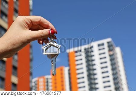 Real Estate Agent, Home Keys In Female Hand On Background Of New Building. Byung Apartment Or Rentin