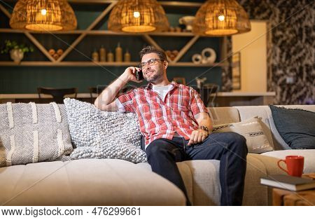 Portrait Of A Cheerful Man With Smart Phone At Night Home. Guy Using Phone At Home. Middle Eastern M