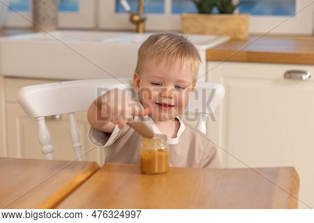 Happy Family At Home. Baby Boy Feeding Himself In Kitchen. Little Boy With Messy Funny Face Eats Hea