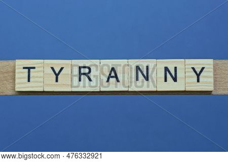 Text The Word Tyranny From Brown Wooden Small Letters On A Black Table