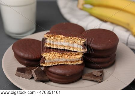 Plate With Tasty Banana Choco Pies And Pieces Of Chocolate On Table, Closeup