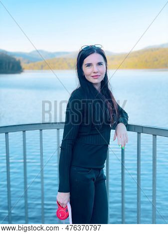 Beautiful Young Relaxed Woman Standing On The River On An Autumn. Mountains And Lake Landscape. Maro