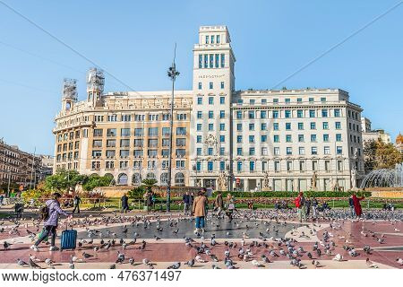 Barcelona, Spain - November 26, 2021: Tourists Walk Among The Many Pigeons Near The Iberostar Hotel 