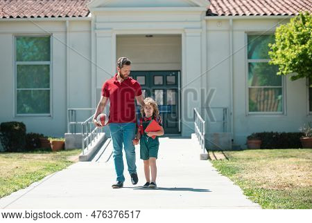 Parent And Pupil Of Primary School. Teacher And Cute Schoolboy With Backpack Near School Park.